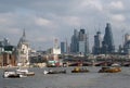 River barges on the thames in late afternoon with the city of london modern financial buildings and historic center visible in the