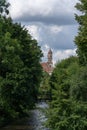 River bed of the Vilnia River lined with lush deciduous trees and  the tower of  Vilnius St. Virgin Maria `s Church in the backgro Royalty Free Stock Photo