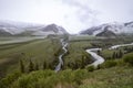 River beds flowing through a green valley with mountains covered with snow on the horizon. Travel Kyrgyzstan Royalty Free Stock Photo