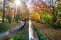 River and bicycle path in the city park in autumn. Sun rays shining through the branches of trees. Royalty Free Stock Photo