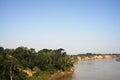 River tied up to pier along muddy and grassy river bank with view to other shore in Puerto Maldonado in Peru and the Amazon