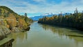 River, bridge and forests with snow capped mountains Royalty Free Stock Photo