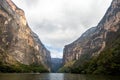 river in a canyon with high walls and florid green vegetation. walls that converge at a point in a canyon