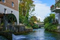 River in the city among buildings. On the left bank is a wheel of an old water mill Royalty Free Stock Photo