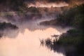 River in the early morning at dawn. Delicate dawn sky and fog rising above the water, lush greenery on the banks. Royalty Free Stock Photo