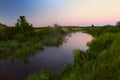 River in the early morning at dawn. Delicate dawn sky and fog rising above the water, lush greenery on the banks. Royalty Free Stock Photo