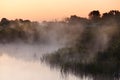 River in the early morning at dawn. Delicate dawn sky and fog rising above the water, lush greenery on the banks. Royalty Free Stock Photo