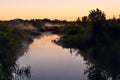 River in the early morning at dawn. Delicate dawn sky and fog rising above the water, lush greenery on the banks. Royalty Free Stock Photo