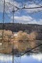 River flow with reflections of blue sky and trees in spring with visible Vilnius television tower on the background Royalty Free Stock Photo