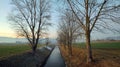 River flowing between an avenue of bare trees in winter