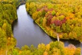 River flows along mixed forest in fall, aerial landscape. Colorful surroundings