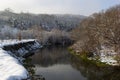 The river flows through the forest. In late fall in the forest the trees stand leafless and reflected in the water of the river