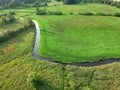 River flows through the green meadow with trees, aerial view