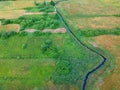 River flows through the green meadow with trees, aerial view