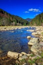 River flows by rocky shore near the autumn mountain forest Royalty Free Stock Photo