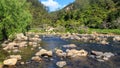 A river full of rocks and boulders runs through a hilly landscape, New Zealand