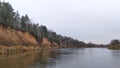 A river landscape in November. The high river bank with sandy bluffs is overgrown with birches and pines. The wind creates ripples Royalty Free Stock Photo