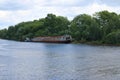 River with lonely rusty cargo ship dire straits among bushes and