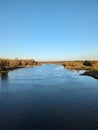 The river meanders through a pristine landscape, embraced by lush greenery and under the expansive canvas of a clear blue sky.