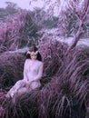 A river nymph in a white lace dress sits in a tall grass by the lake. The princess has a beautiful wreath. Fantastic Royalty Free Stock Photo