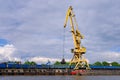 River port crane with clamshell or griper loading coal to river drag boats or barges moored by pier on cloudy day Royalty Free Stock Photo