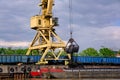 River port crane with clamshell or griper loading coal to river drag boats or barges moored by pier on cloudy day Royalty Free Stock Photo