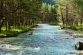 The river with rifts flows into the wooded foothills