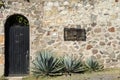 River rock house wall black door and agave plants