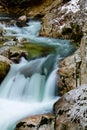 River rocks in smooth satin water flow of waterfall in wintertime Royalty Free Stock Photo