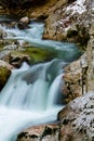 River rocks in smooth satin water flow of waterfall in wintertime Royalty Free Stock Photo