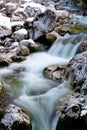 River rocks in smooth satin water flow of waterfall in wintertime Royalty Free Stock Photo