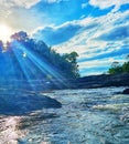 A river running through a lush green forest. sun rays penetrating water and blue rays of light.