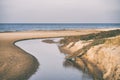 A river in sand dunes flows into the sea Royalty Free Stock Photo