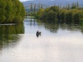 River scene leading into hinterland and hills with one man paddling canoe