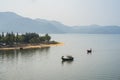 River scene in Vietnam, with fishing boat, strip of land and mountain on background