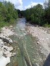 River Setta with fallen tree trunks protruding as in 3D and rocks on the sides in Monzuno Appennino Italy