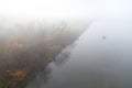 River shore leads into the fog, alm waters reflect the trees, lonely fishing boat. Ukraine.