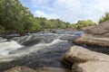 The river Southern Bug in the summer - rocky shores, rapids, fast river flow, bright green vegetation and a cloudy blue sky Royalty Free Stock Photo