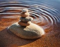 A river stone balancing on top of a bed of sand next to rippling water Royalty Free Stock Photo