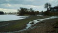 River thames at low tide on grey overcast day with small stream and pebble beach Royalty Free Stock Photo