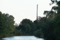 River Turiec in town Martin in north Slovakia with wild vegetation on both banks. On the horizon there is a tall chimney of heat a