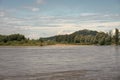 River water with horse, green trees, hills on blue sky