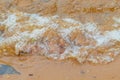 River wave with foam washes the sandy bank of the river in the city in the summer