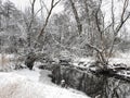 River in Winter: Water in a small river runs through a snow covered prairie with a few bare trees along the banks of the river on Royalty Free Stock Photo