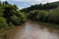 The river with yellow muddy water flows between the shores covered with trees and greenery. Royalty Free Stock Photo