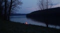 Riverbank campfire twilight, serene nature scene Royalty Free Stock Photo
