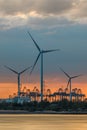 Riverbank with large windmills and silhouettes of container cranes during sunset, Port of Antwerp Royalty Free Stock Photo