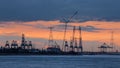 Riverbank with silhouettes of container terminal cranes during a sunset, Port of Antwerp, Belgium Royalty Free Stock Photo