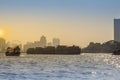 Riverfront view of tug boat drags cargo barge on Chao Phraya river in Bangkok, Thailand. Royalty Free Stock Photo