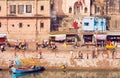 Riverside of indian city with crowd of busy people, riverboats and marketplaces